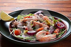 Sea food salad with shrimps, avocado, cherry tomatoes, red hot chilly pepper, red onion, arugula, beet leaves,