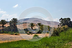 Sea of Galilee view from the coastal strip to the mountain and palm trees July