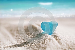 Sea glass blue heart on white sand beach