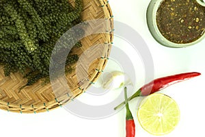 Sea grapes or green caviar and spicy sauce on a white dish isolated on white background