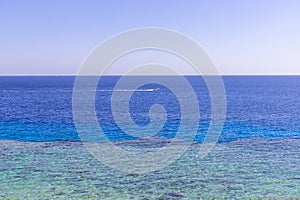 Sea horizon and a boat floats by. The bright blue sea. Snorkeling on the Red Sea in Egypt. Turquoise water by the sandy beach and