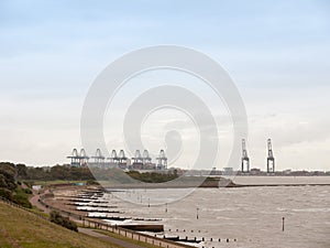 sea industry cargo and shipping cranes in the distance beach groynes Harwich Port
