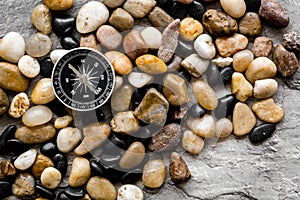 Sea journey, travelling and vacation concept. Compass on rocks and grey background top view