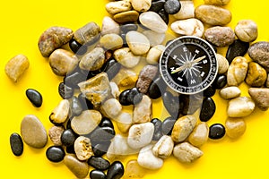 Sea journey, travelling and vacation concept. Compass on rocks and yellow background top view