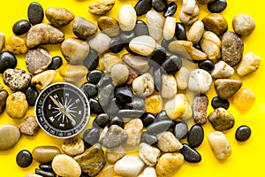 Sea journey, travelling and vacation concept. Compass on rocks and yellow background top view