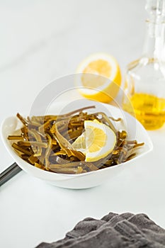 Sea kale kelp salad with oil and lemon in a white plate, white b