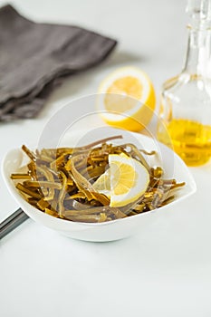 Sea kale kelp salad with oil and lemon in a white plate, white b