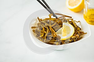 Sea kale kelp salad with oil and lemon in a white plate, white b