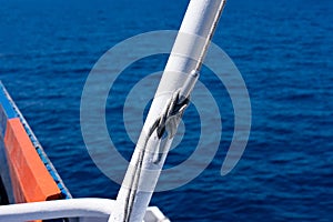 Sea knot on a white flagpole on sail boat on water surface background with lot of wave