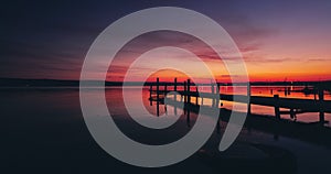 Sea lake sunset over old wooden jetty pier on shore,relaxing nature landscape