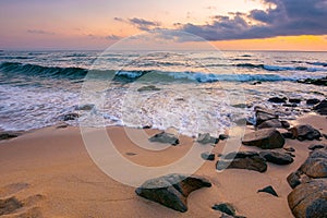 Sea landscape at dawn. rocks on the sandy beach. clouds on the sky