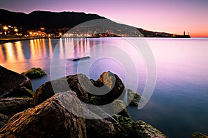 Sea landscape during sunrise with city lights