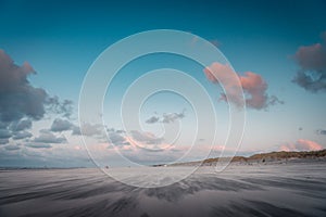 Sea landscape, during sunset, shifting sands, clear blue cloudy sky on the beach,