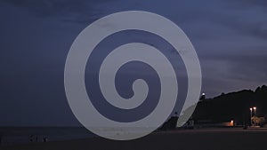 The sea lighthouse in Calella at night turns and gives rays of light. Spain.