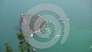 Sea liner and small ships near rocky island on azure sea