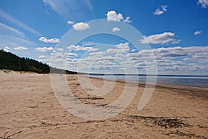 Sea with long sandy coastline and blue sky with clouds