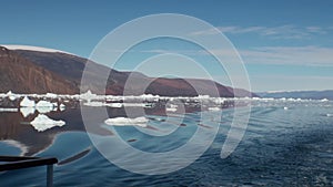 Sea mountains and large icebergs reflecting water.