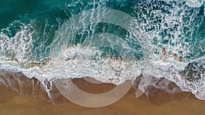 Sea or ocean surf wave. Foamy ocean waves rolling and coming on a sand beach. Aerial top down shot, 4K