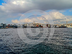 Sea panorama of Istanbul Turkey with Galata tower among city buildings on a cloudy summer-autumn day. The Bosphorus coastline