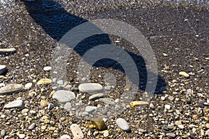 sea pebble beach with multicoloured stones, waves with foam