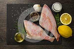 Sea perch on a black board. Sea ??bass on a black board with the ingredients for it cooking. Fish on the table. Ocean perch