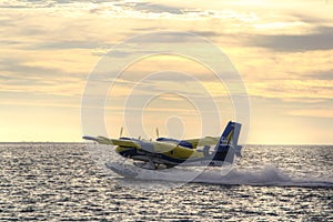 Sea plane taking off at sunset