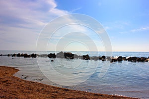 Sea and rocks. A beach with a view of the stones in the sea. Blue sea with a sandy line. Ocean horizon