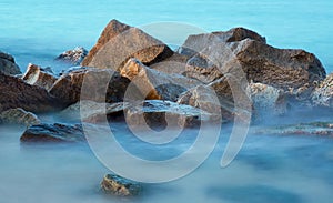 Sea rocks in haze at sunset