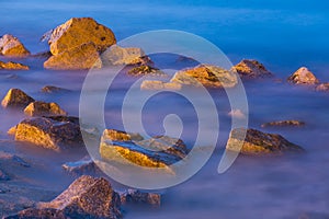 Sea rocks in haze at sunset