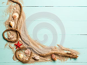 Sea rope with many different sea shells on the sea sand on a blue wooden background. Top view