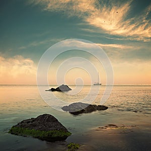 Sea and sailboat on horizon with cloudy sky