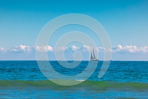 Sea and sailing wind boat. Sailboat over blue waves and sunny sky