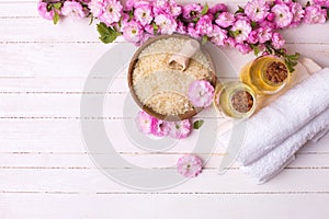 Sea salt in bowl, bottles with aroma oils, towels and pink flowers