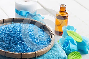 Sea salt in bowl with candle and towels on wooden background