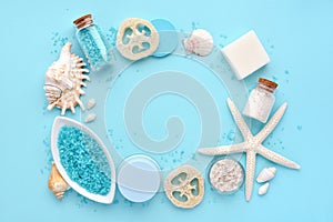 Sea salt, cream, lotion, soap, sponges and shells in cosmetics set for spa on blue background. Spa concept. Top view with space