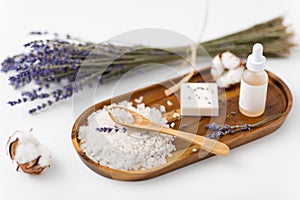 Sea salt, lavender soap and serum on wooden tray