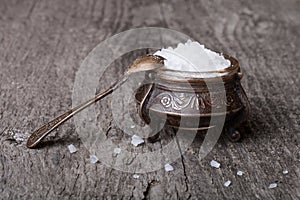 Sea salt in an old utensils and a small spoon on a wooden table