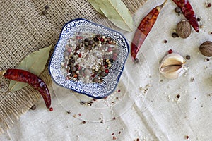 Sea salt and spices in small blue plate  chilli  Bay leaf  close-up  on rough linen background