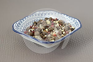 Sea salt and spices in small blue plate with pattern, chilli, Bay leaf, close-up, on light grey linen background