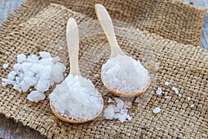 Sea salt in wooden spoon on burlap sack