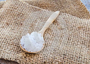 Sea salt in wooden spoon on burlap sack