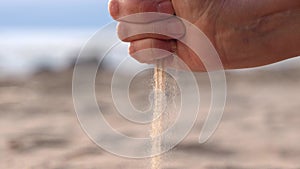 sea sand pours from a woman's hand on the sea beach. lost time