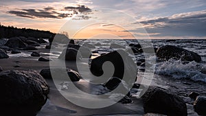 Sea sandy beach with granite boulders at sunset twilight.