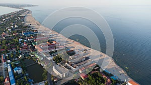 Sea sandy beach with people resting at sunrise in summer. Aerial view. Bird's-eye view of the sea coast.