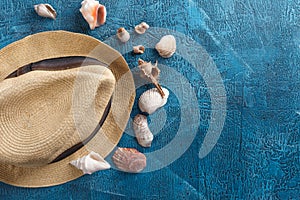 Sea shells, beach hat on blue wooden background