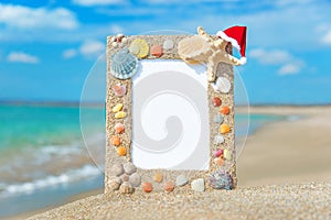 Sea shells frame with christmas hat against sea beach