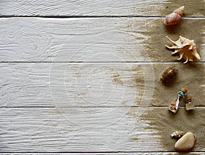 Sea shells, pebbles and sand on a white wooden background.