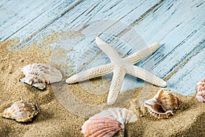 Sea shells and starfish on a blue wooden background and sand