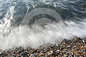 Sea shock wave foam on the pebble stone beach