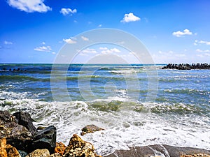 Sea shore with blue water, rocks and mistic summer sky
